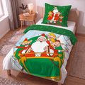 Weihnachtsmann & Co. KG Bettwäsche ‘Nordpol-Helden’ aus Flanell auf einem Einzelbett: Bettbezug mit dem Weihnachtsmann und den Elfen im Schlitten, oben umgeschlagen mit der grünen Tannen-Rückseite, dahinter der Kissenbezug
