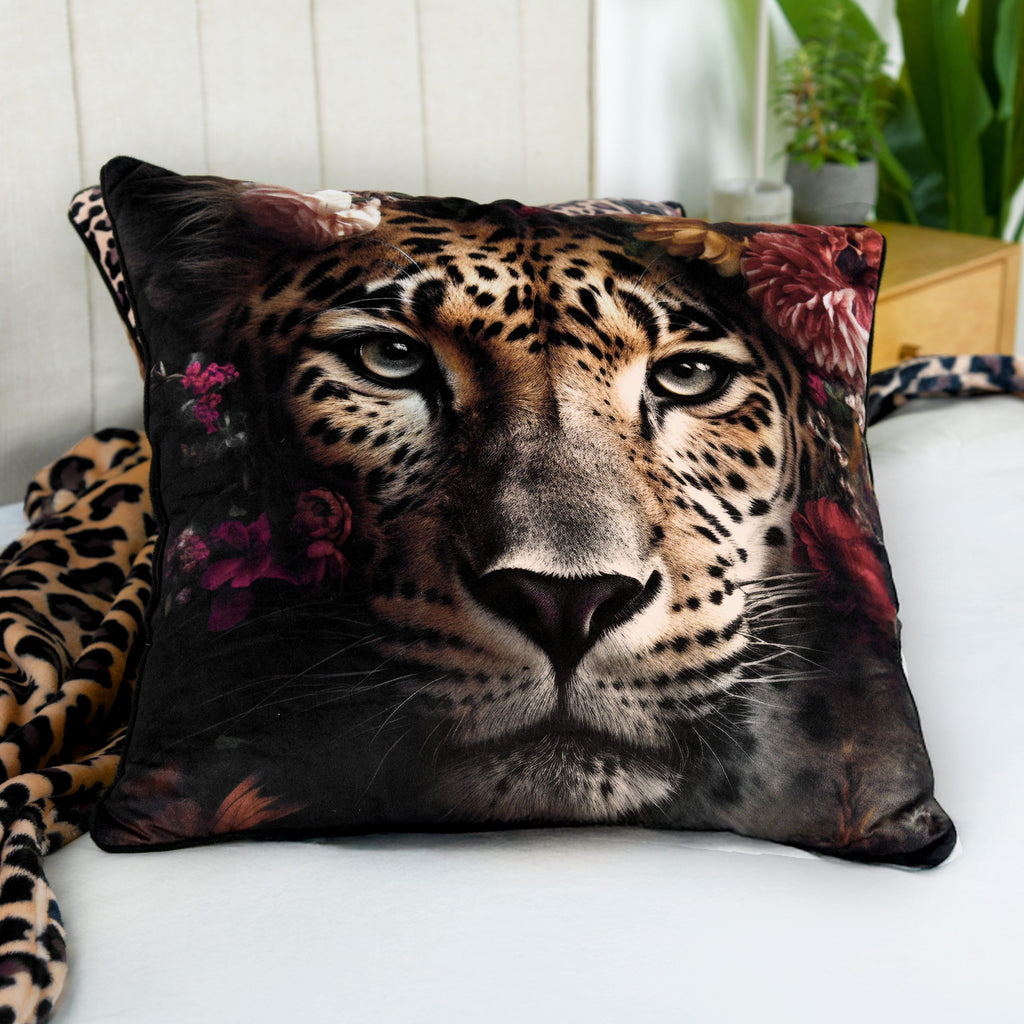 Wild Flowers Dekokissen ‘Leopard’ auf einem Bett mit weißem Laken, daneben eine Decke mit Leoprint