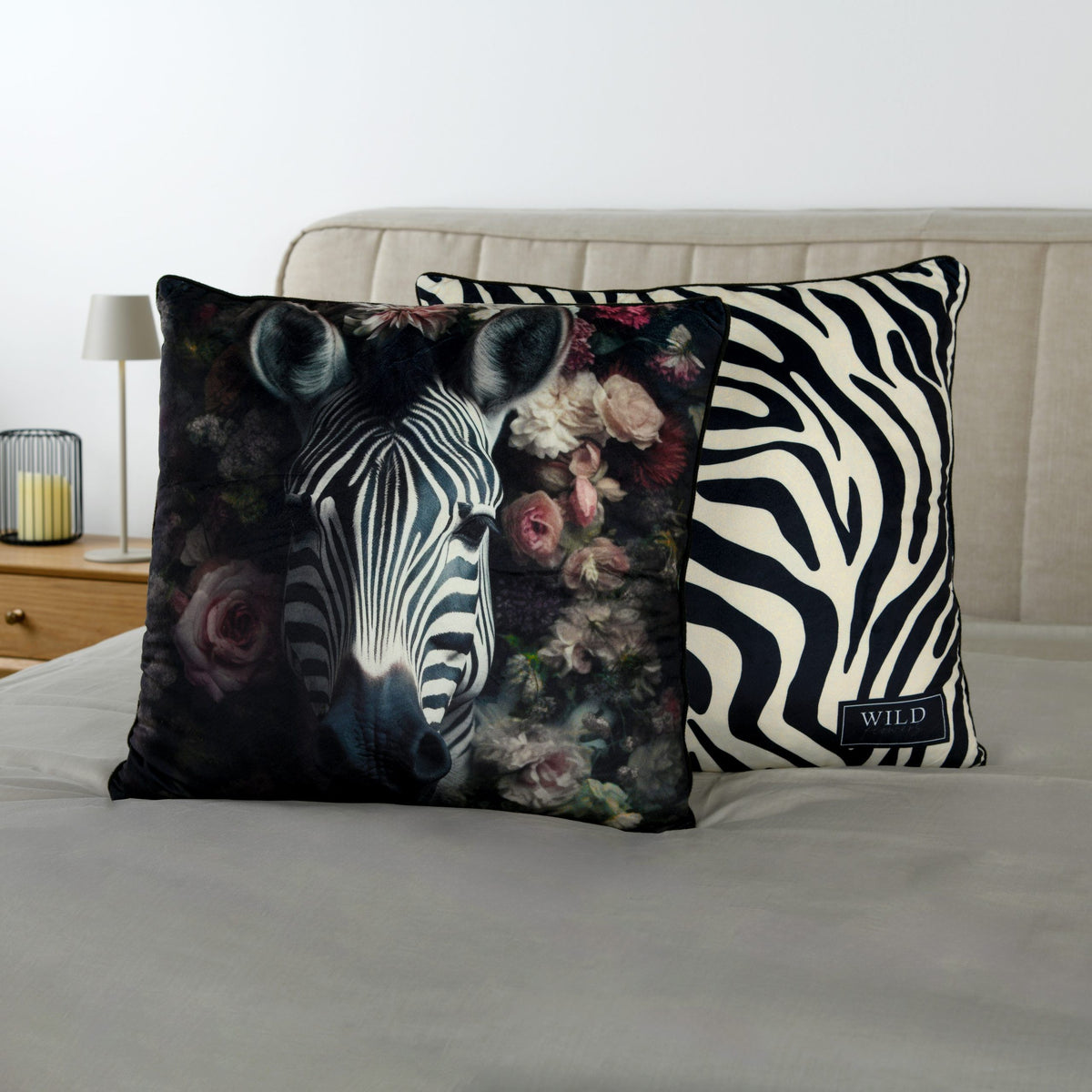 Wild Flowers Dekokissen ‘Zebra’ mit beiden Seiten auf einem Bett mit grauer Bettwäsche