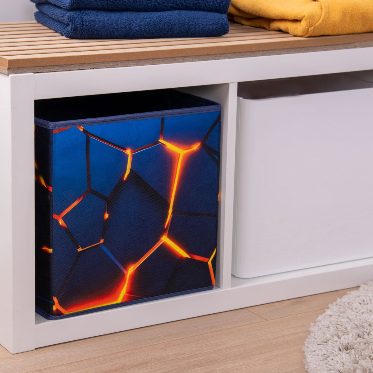 Aufbewahrungsbox ‘Lava 3D Effekt’ in einem weißen Regalwürfel, darauf gefaltete Handtücher