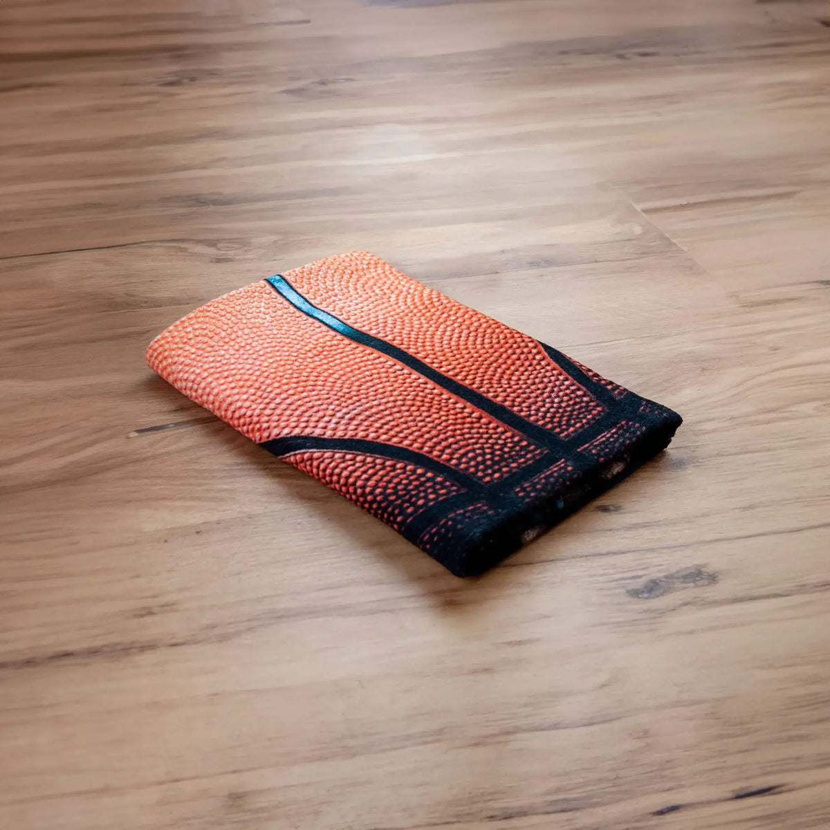 Young Collection Badetuch ‘Basketball’ gefaltet auf Holzboden