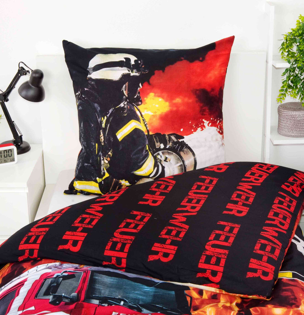Kissen mit Feuerwehrmann im Einsatz und Wendeseite der Feuerwehr-Bettwäsche auf einem Bett