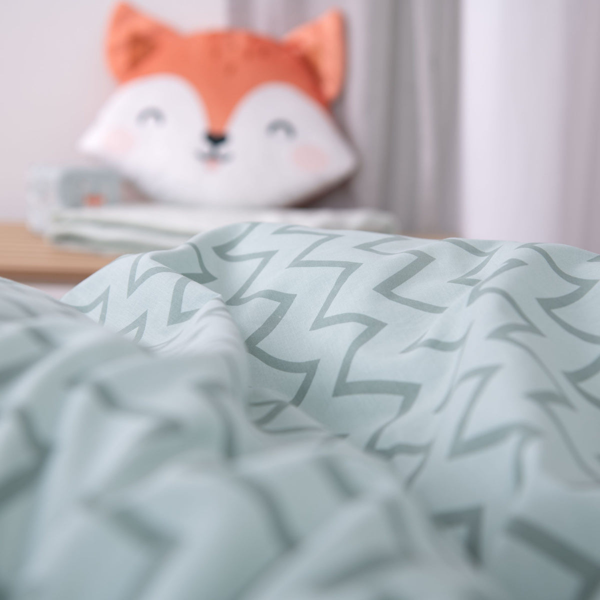 Nahaufnahme des Zickzack-Musters in Salbei mit Fuchs-Kuscheltier