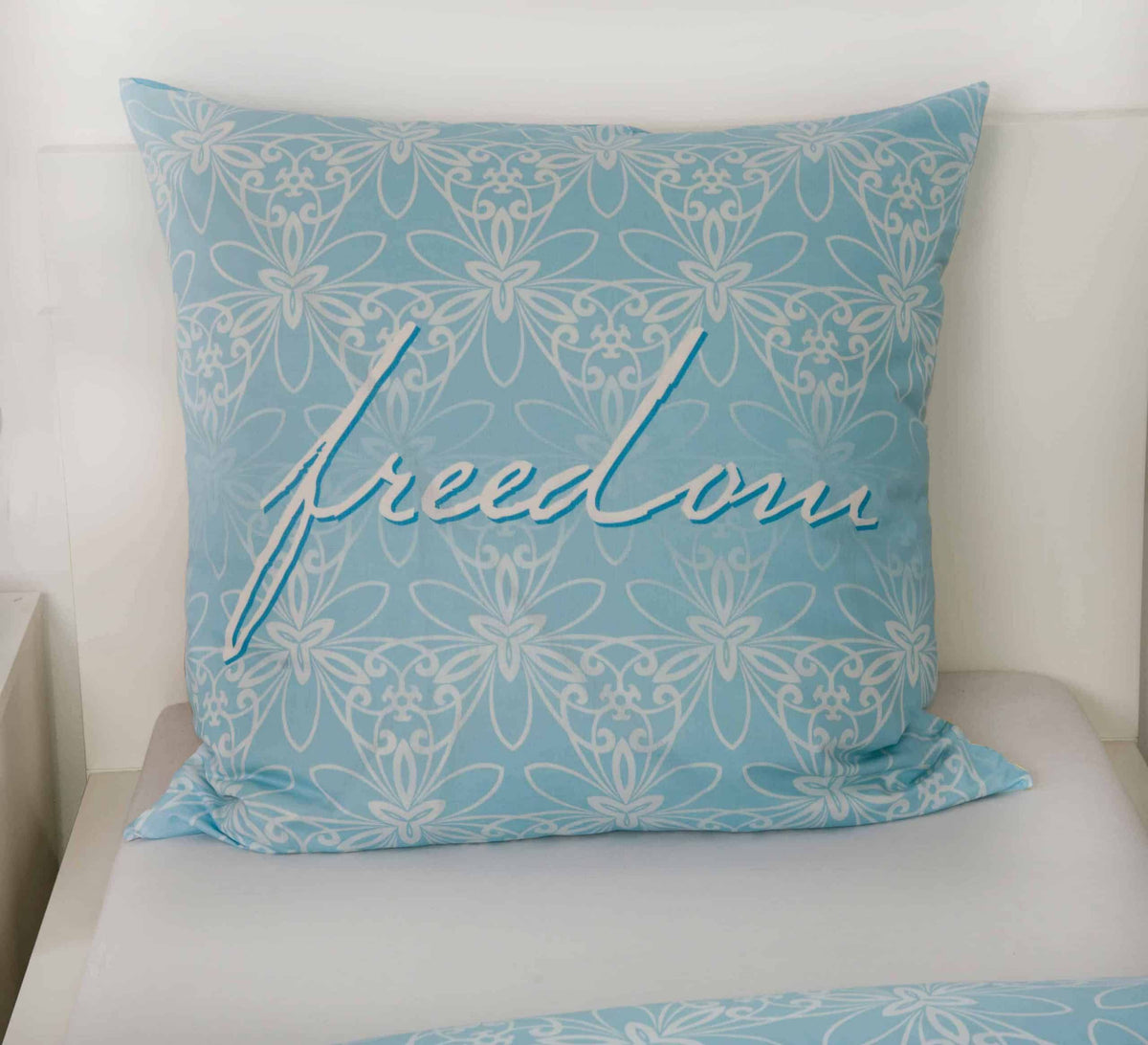 Kissen 80 x 80 cm mit Schriftzug „freedom“ auf hellblauem Ornament