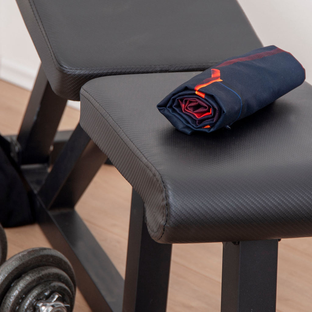 Zusammengerolltes Fitnesstuch ‘Lava 3D Effekt’ auf einer Hantelbank