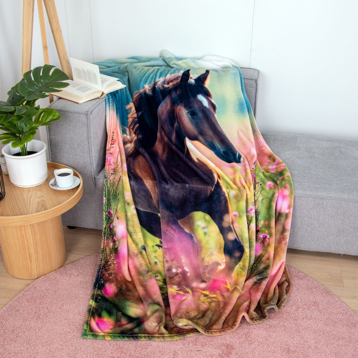 Young Collection Kuscheldecke ‘Pferdeglück’ über einem grauen Sofa