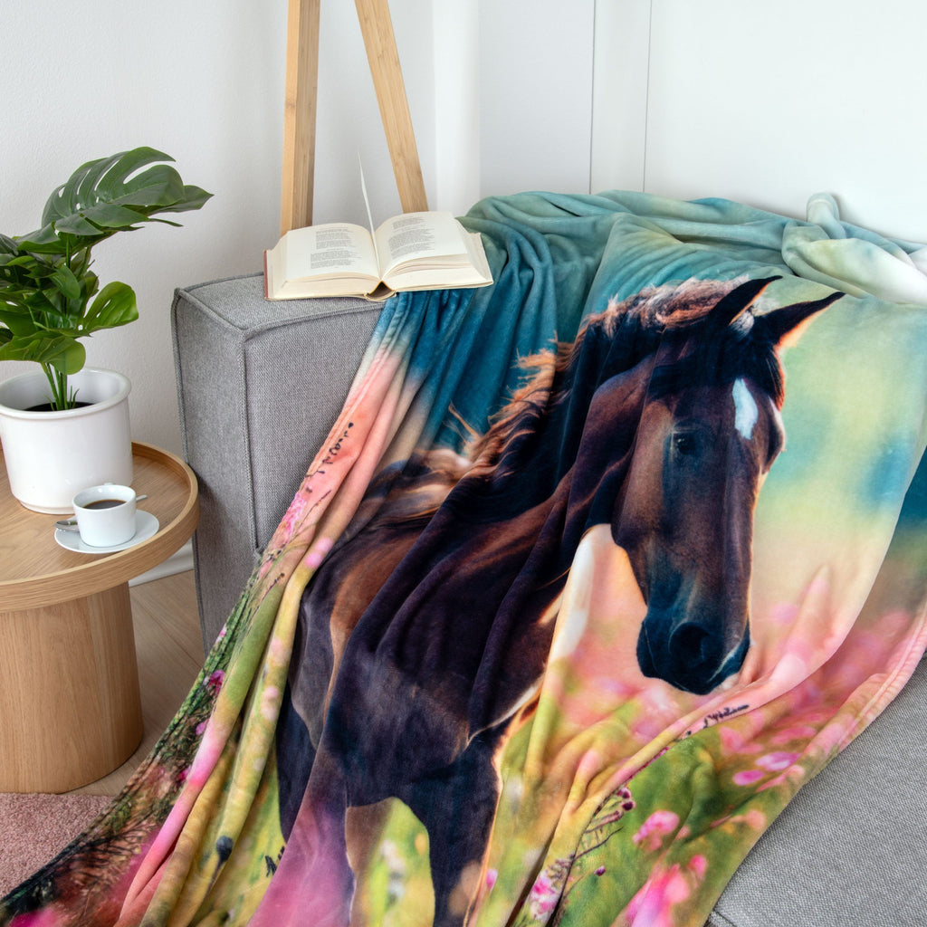 Kuscheldecke ‘Pferdeglück’ über dem Sofa, der Pferdekopf groß im Bild